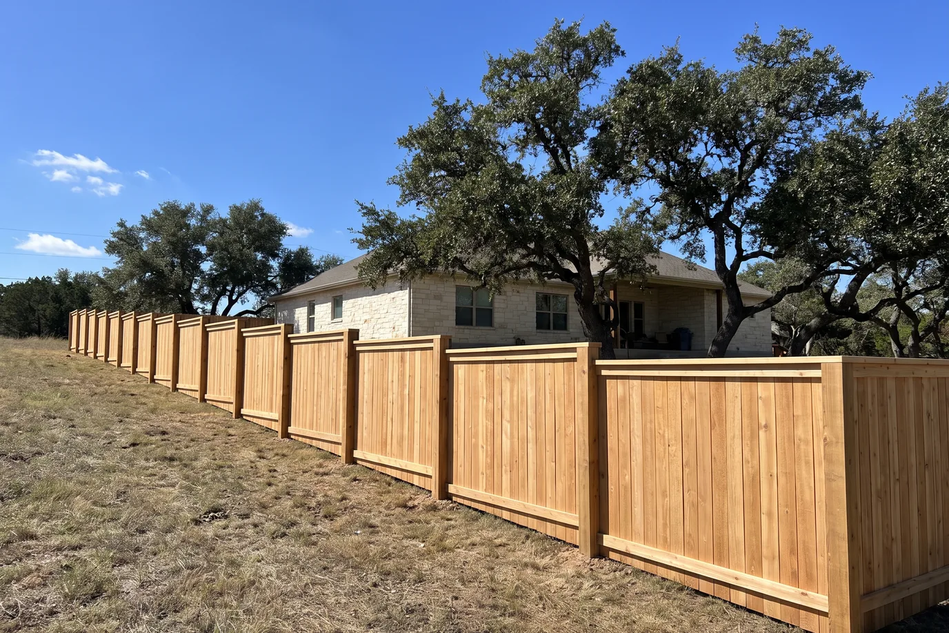 A new cedar privacy fence stepping down a gentle slope in level sections, with a kickboard following each step